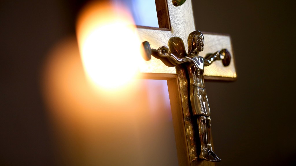 Eine Kerze vor einem Kreuz mit einer Jesusfigur