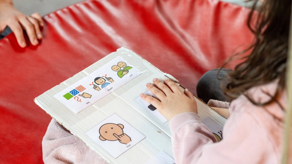 Förderschule. Schülerin hält eine Tafel mit der Symbolen für nonverbale Kommunikation in der Hand.