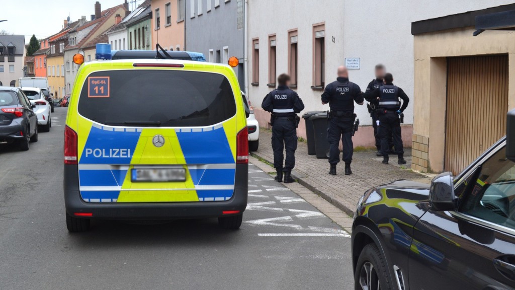 Polizeieinsatz in der Innenstadt von Neunkirchen. Polizisten stehen neben dem Einsatzfahrzeug.