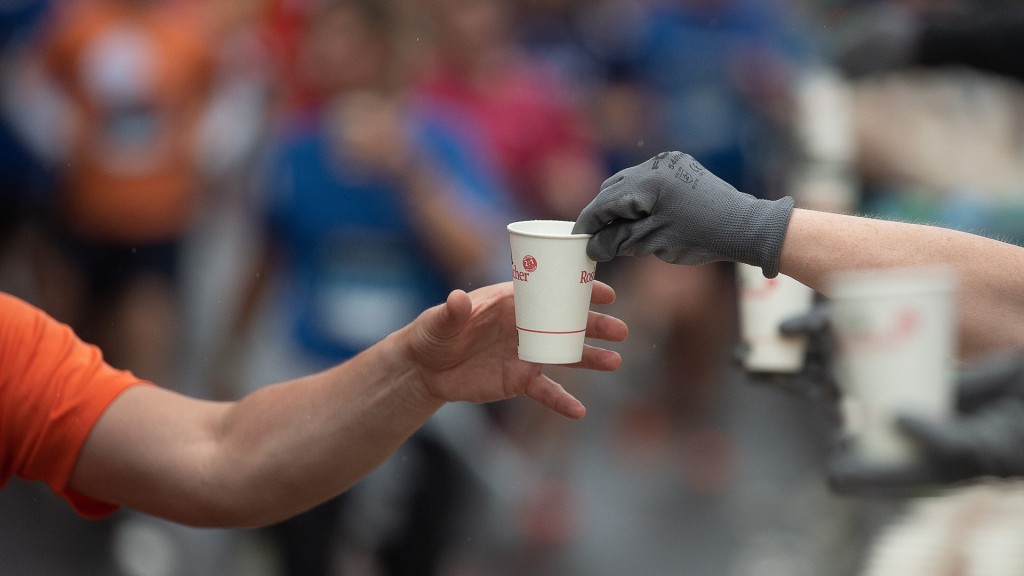Foto: Ein Läufer nimmt während des Firmenlaufs einen Einweg-Becher mit Wasser von einem Helfer entgegen.