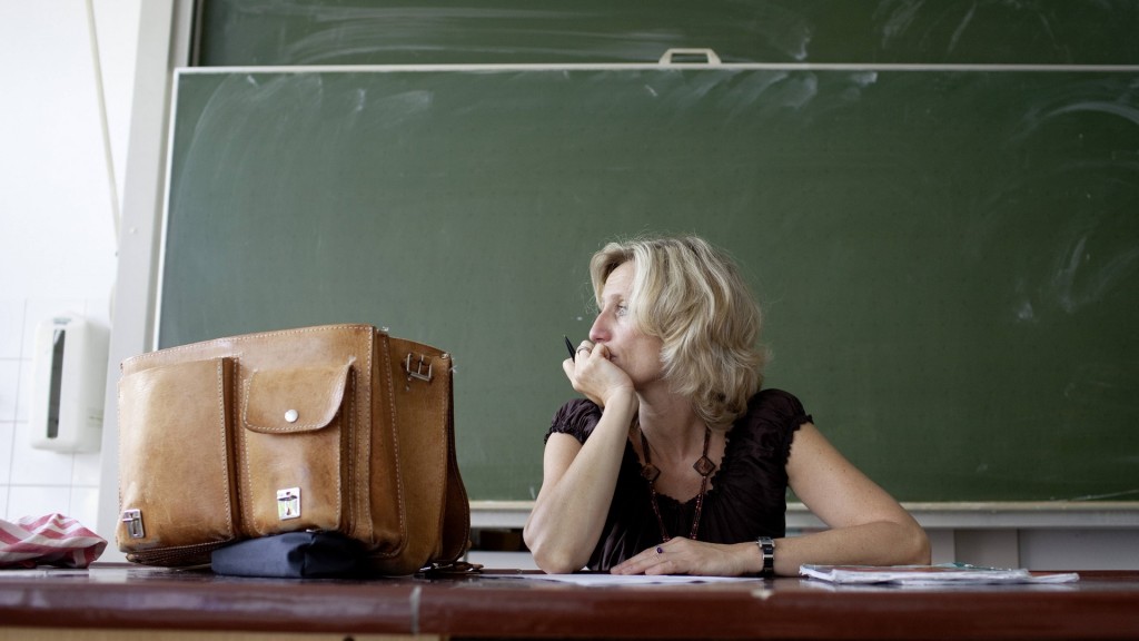 Lehrerin am Pult mit nachdenklichem Gesichtsausdruck