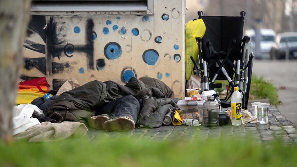 Eine vermutlich obdachlose Person liegt in der Innenstadt unter einem Schlafsack