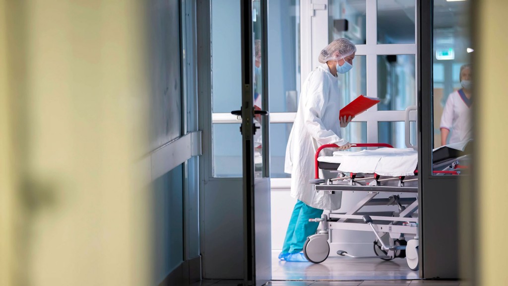 Krankenhauspersonal schiebt ein leeres Patientenbett über den Flur