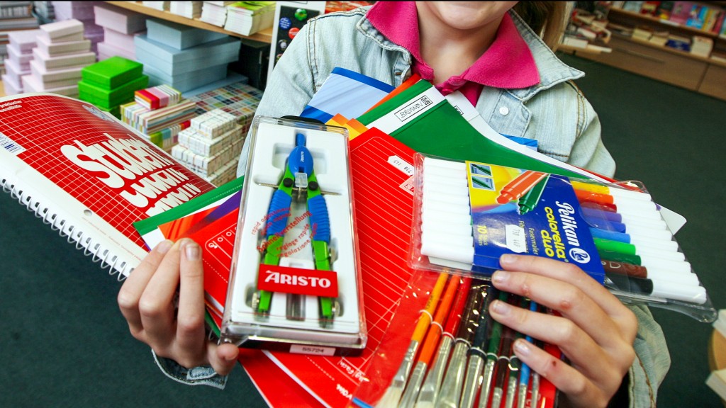 Ein Kind hält verschiedene Schulmaterialien, Stifte und Hefte