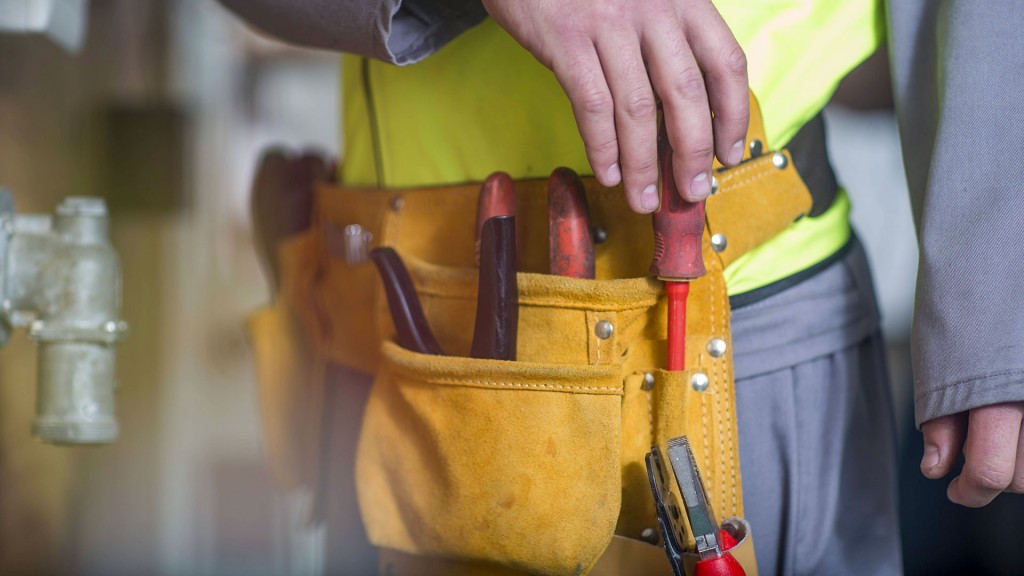 Ein Handwerker zieht einen Schraubendreher aus seinem Werkzeuggürtel