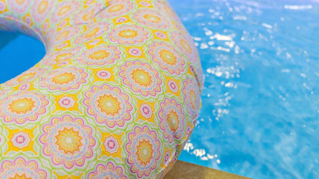 Bunter Schwimmreifen liegt am Rand eines Pools mit klarem Wasser.