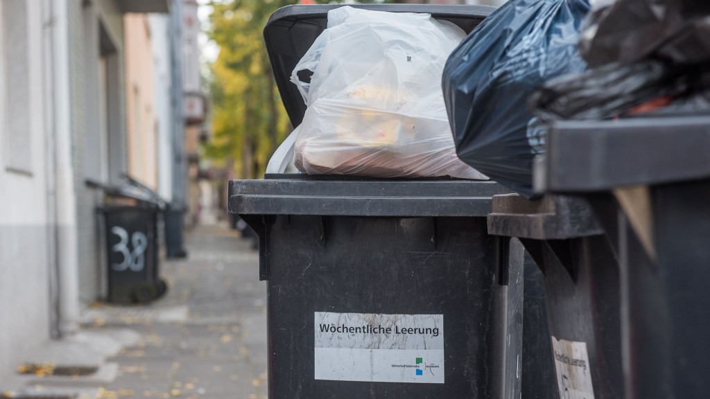 Foto: Mehrere volle Restmülltonnen stehen an einer Hauswand