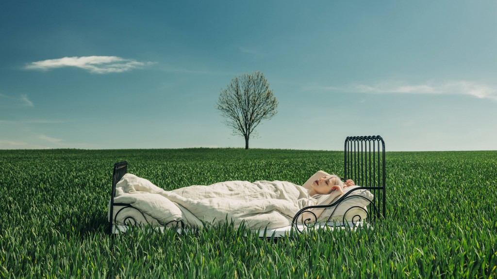 Eine Frau, die im Freien unter blauem Himmel in einem Bett träumt