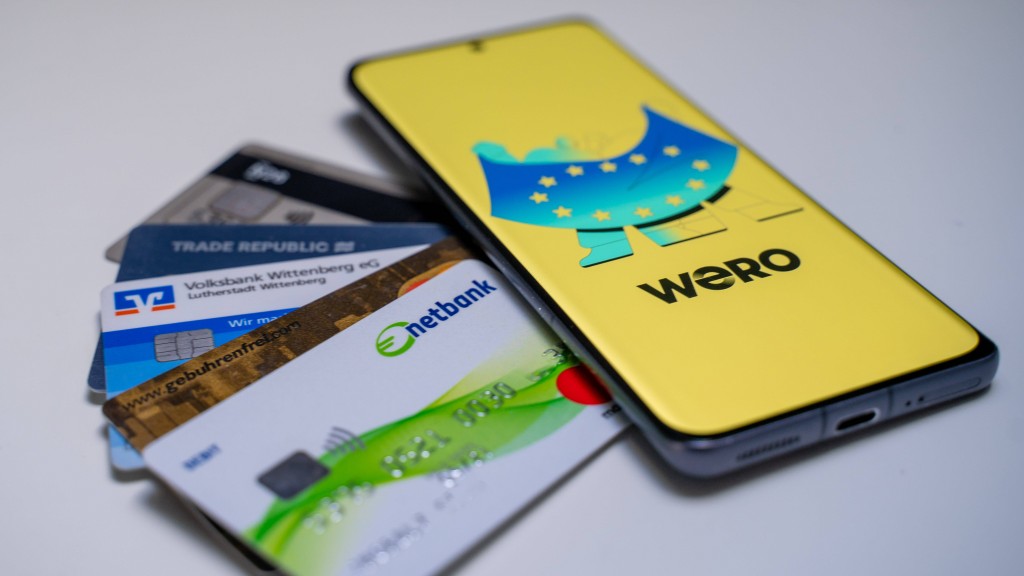 Auf einem Handy ist die App Wero geöffnet. Daneben liegen verschiedene Bankkarten