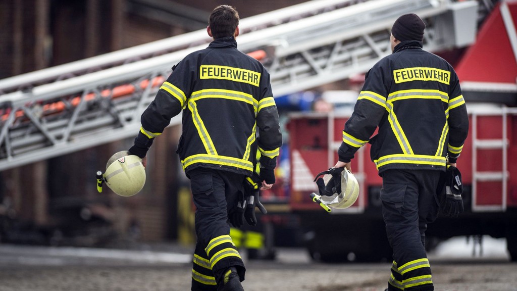 Foto: Zwei Feuerwehrleute gehen zu einem Einsatzfahrzeug