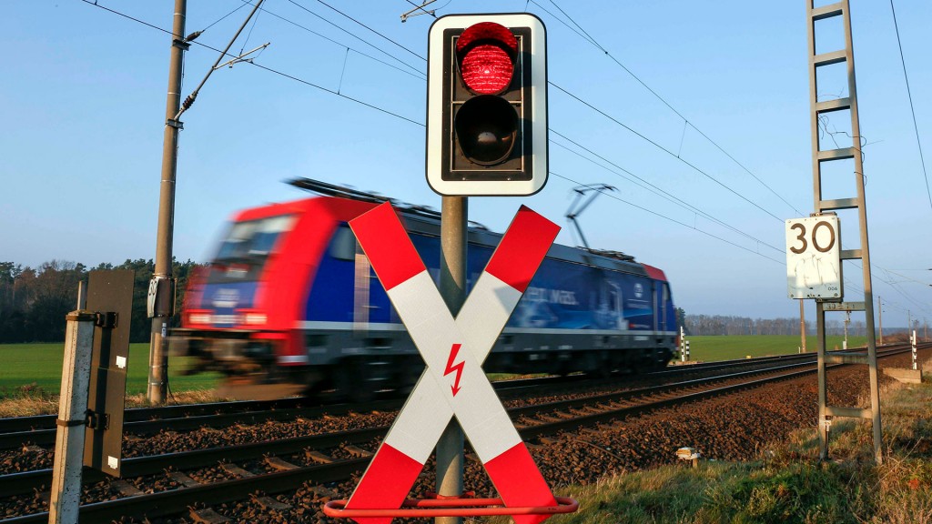 Foto: Eine Lokomotive passiert einen Bahnübergang mit roter Ampel und Andreaskreuz