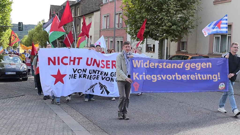 Foto: Teilnehmer der Gedenkfeier laufen mit Bannern durch eine Straße