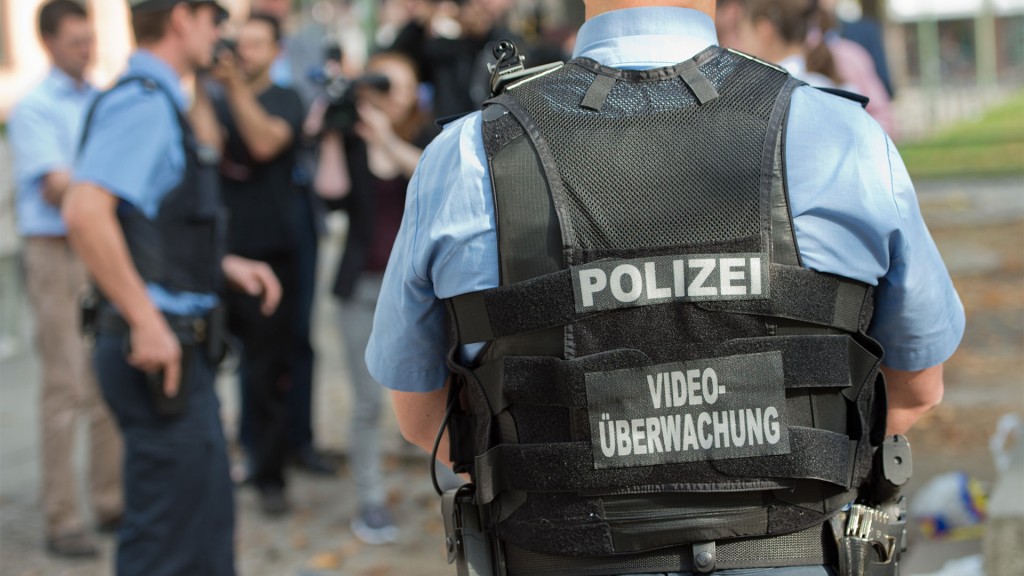 Ein Polizist trägt eine Schutztweste mit der Hinweis 
