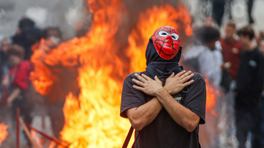 Foto: Mann mit roter Maske vor brennendem Feuer (Bild aus der Stadt Pau im Südwesten Frankreichs)