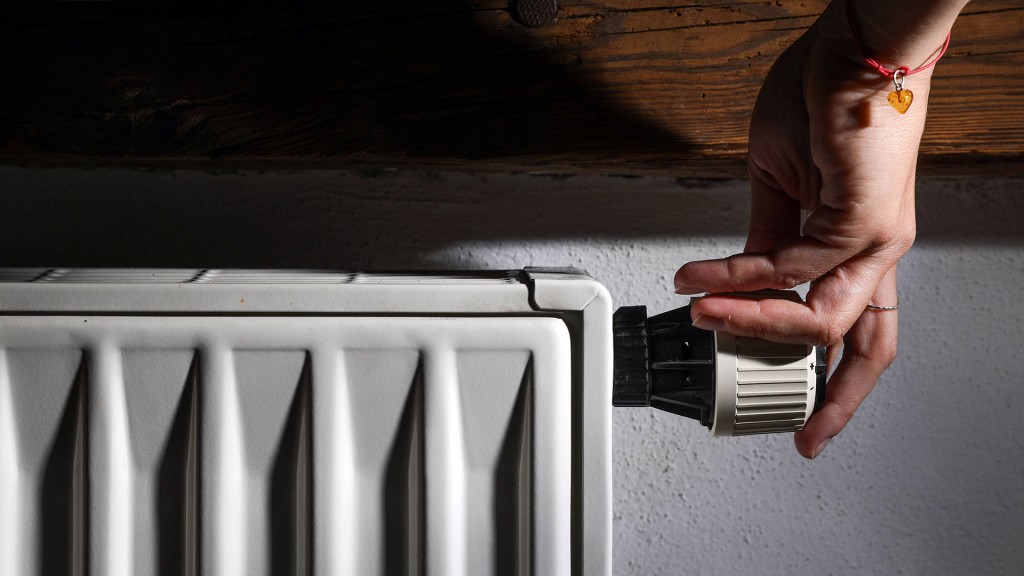 Jemand dreht am Thermostat eines Heizkörpers