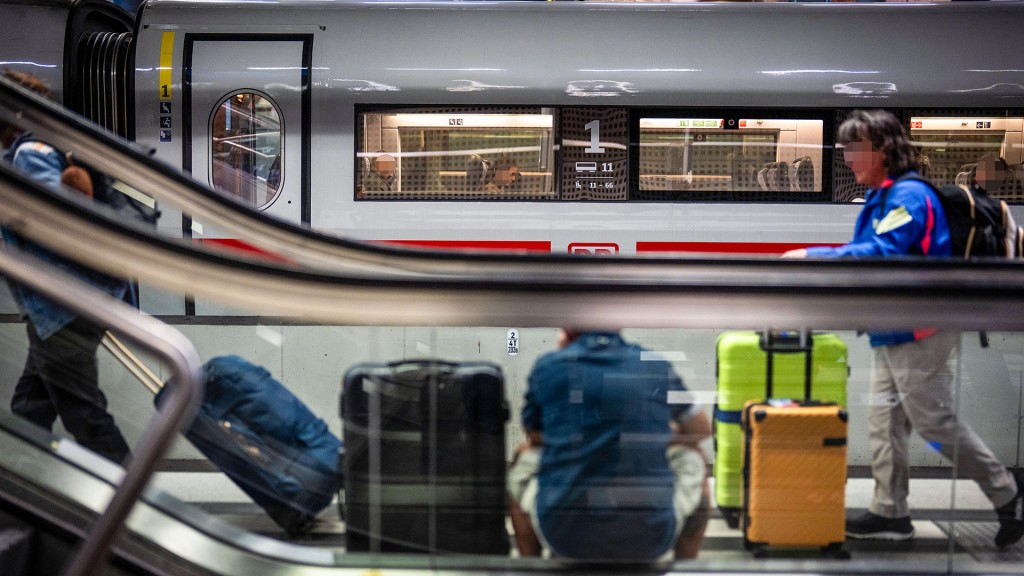 Jemand sitzt mit mehreren Koffern an einem Bahngleis