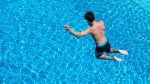 Mann springt von Turm in Schwimmbecken