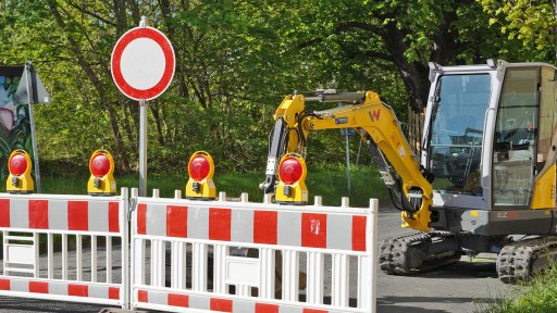 Verkehrszeichen Verbot für Fahrzeuge aller Art, Schrankenzaun und Bagger bei einer Baustelle